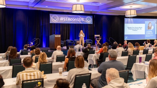 Wide view of a STACon breakout room with a speaker on stage.