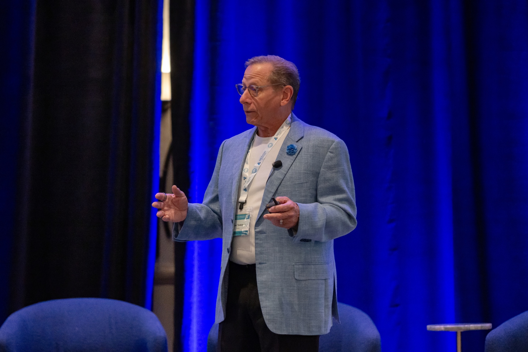 Speaker presenting in front of a deep blue stage curtain at STACon.