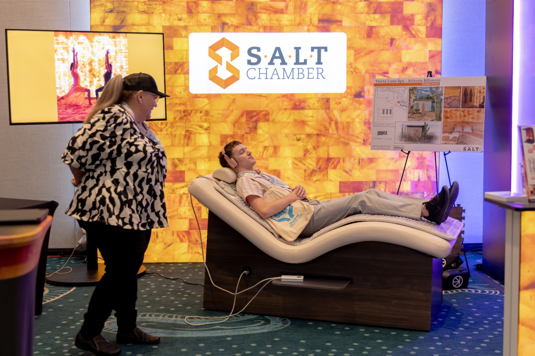 Attendee relaxing on a SALT Chamber sound recliner in front of a Himalayan salt wall.