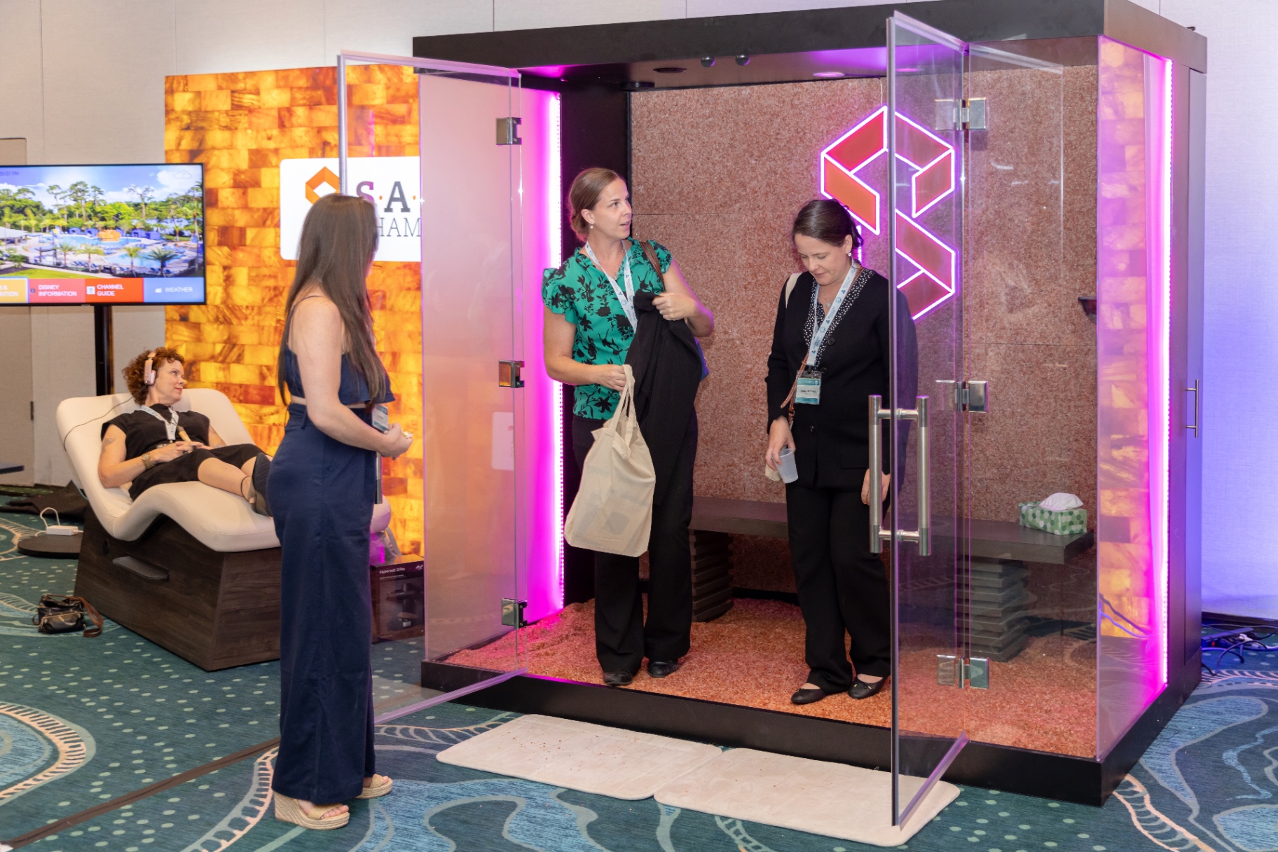 Attendees stepping into a SALT Chamber halotherapy room on the show floor.