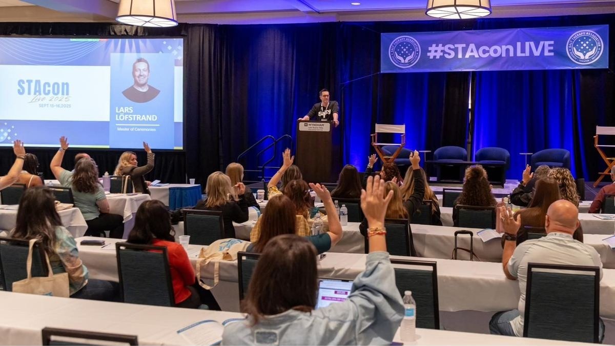Engaged STAcon audience with hands raised during a session.