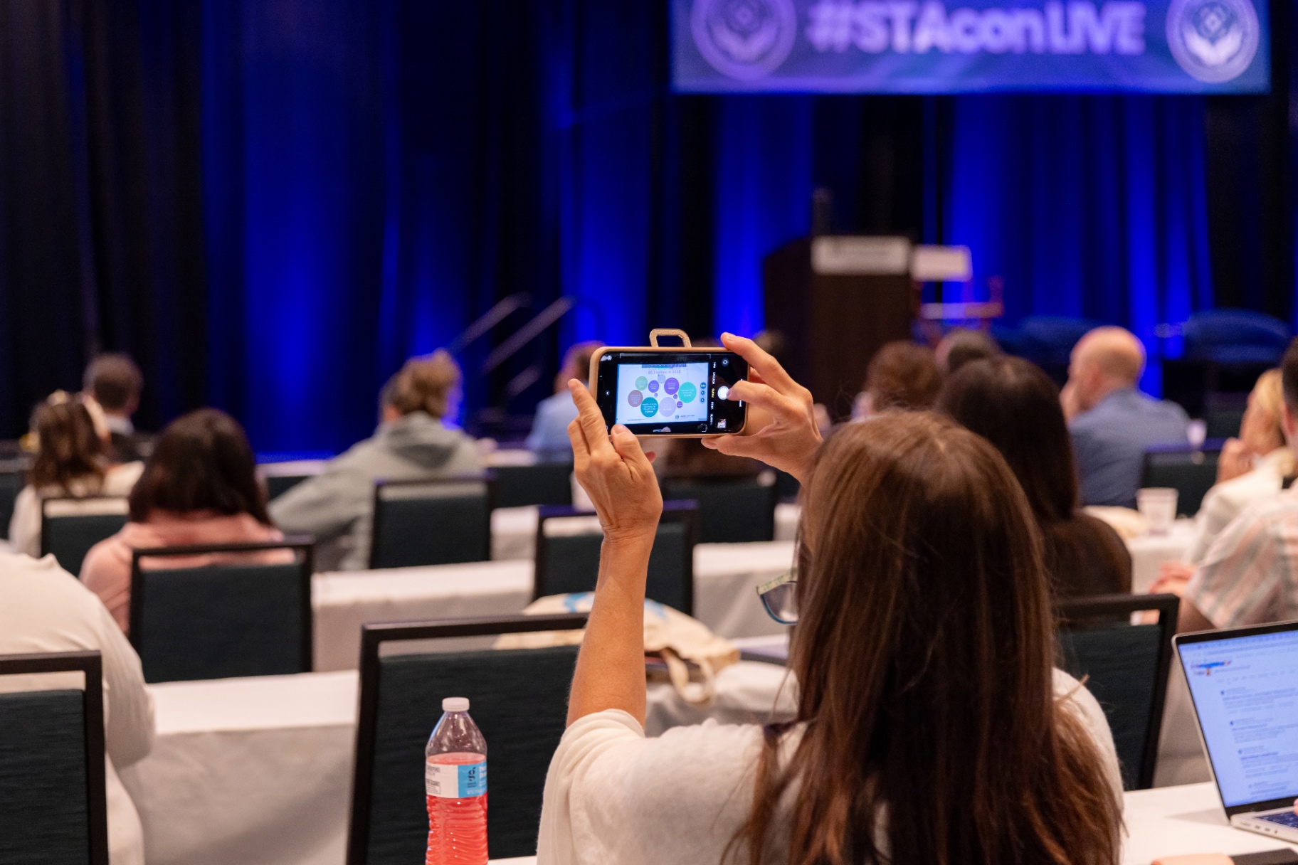 Attendee photographing slides during a STACon keynote.