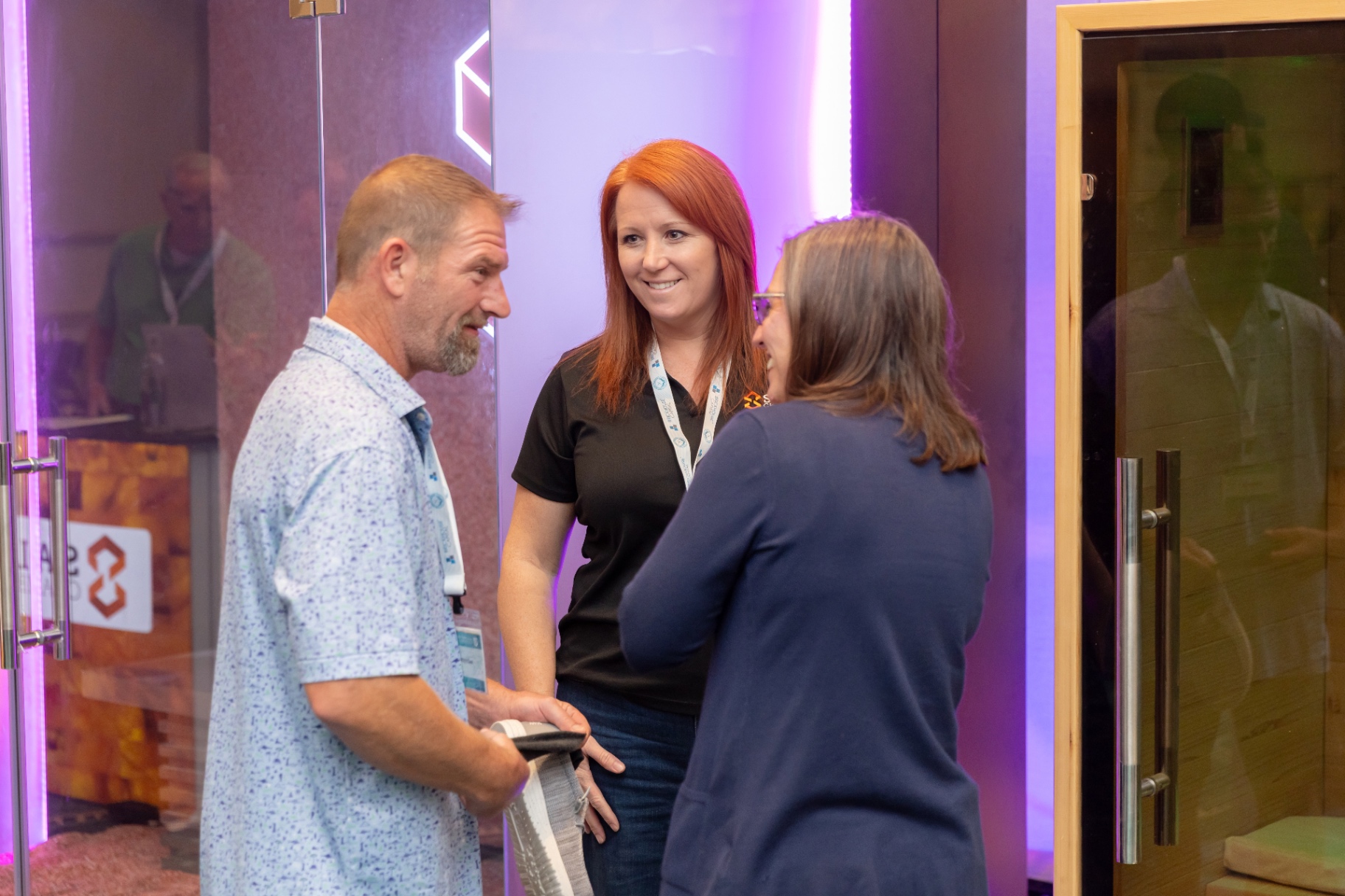 Attendees talking with a SALT Chamber rep inside an illuminated salt booth.